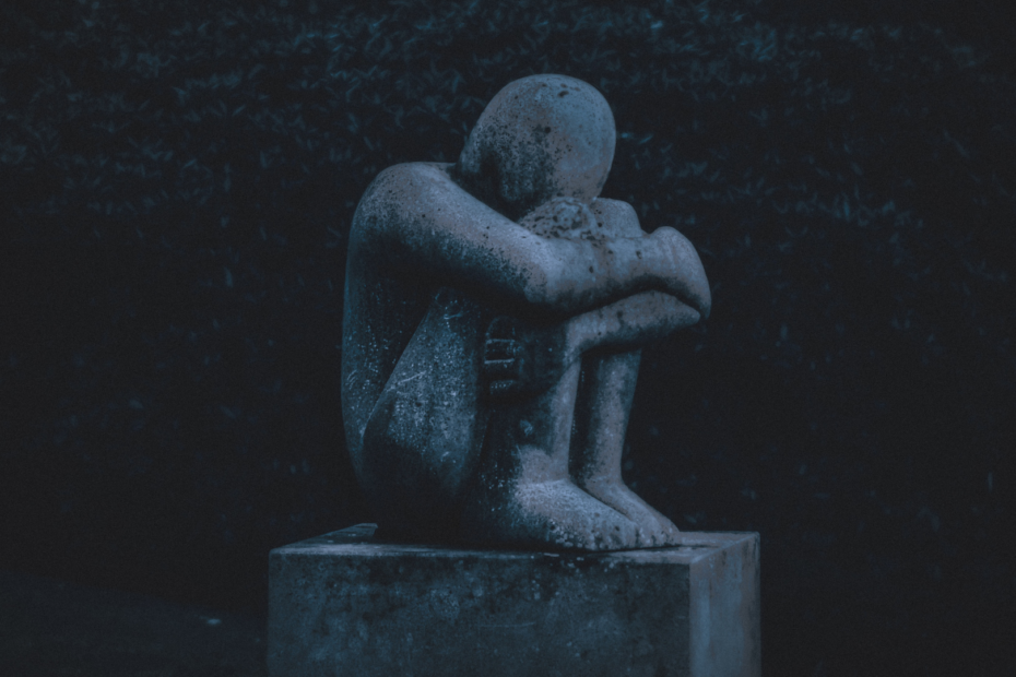 Statue einer traurig hockenden Figur